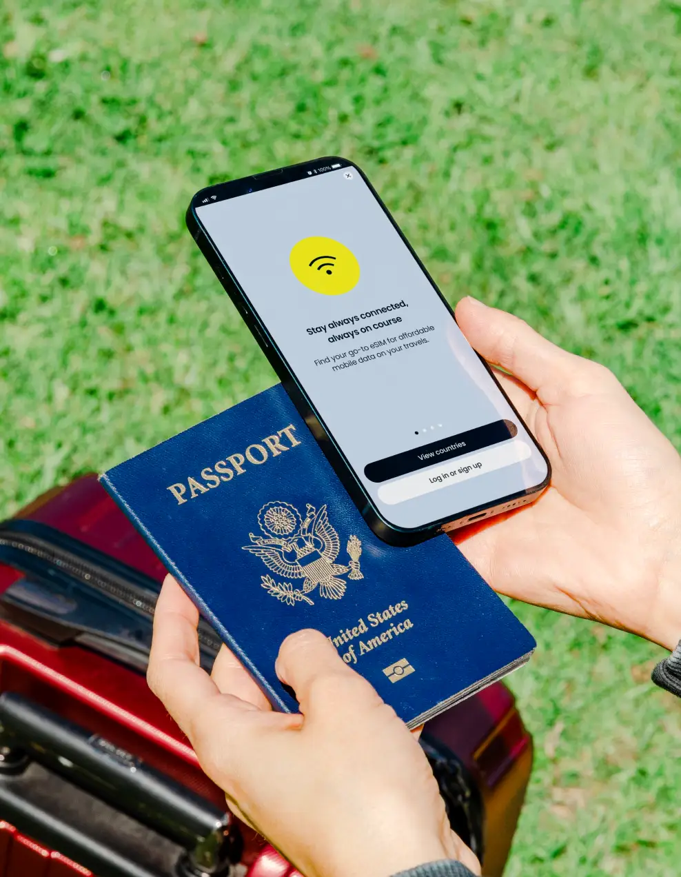 A traveler holding a passport and a smartphone showing an eSIM app, a red suitcase below