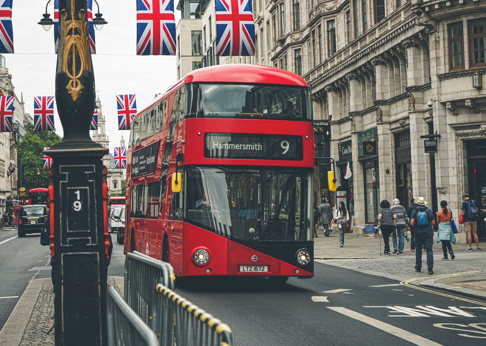 A red double-decker bus on a London street lined with Union Jack flags