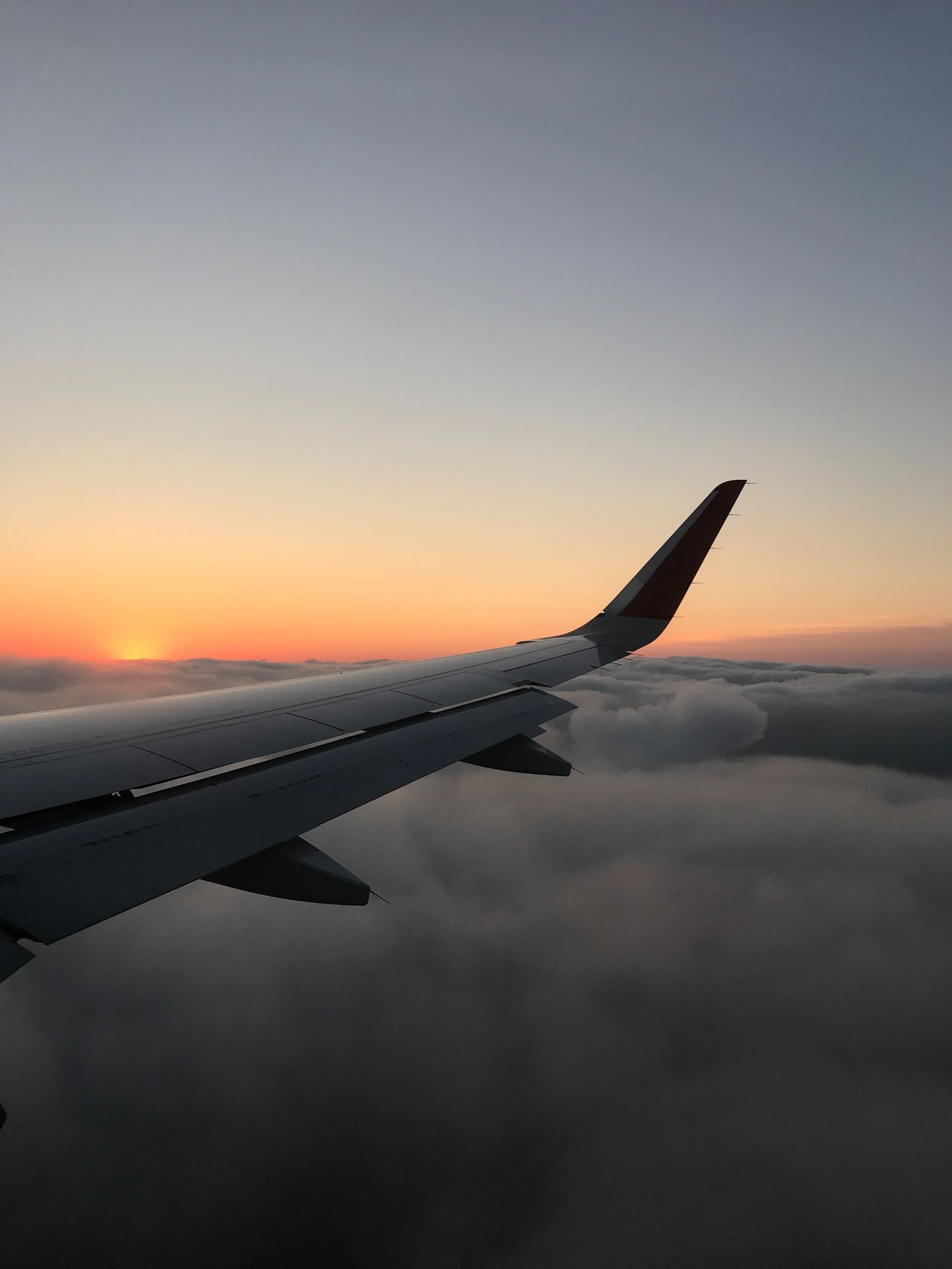 View over an aircraft wing above the clouds at sunset