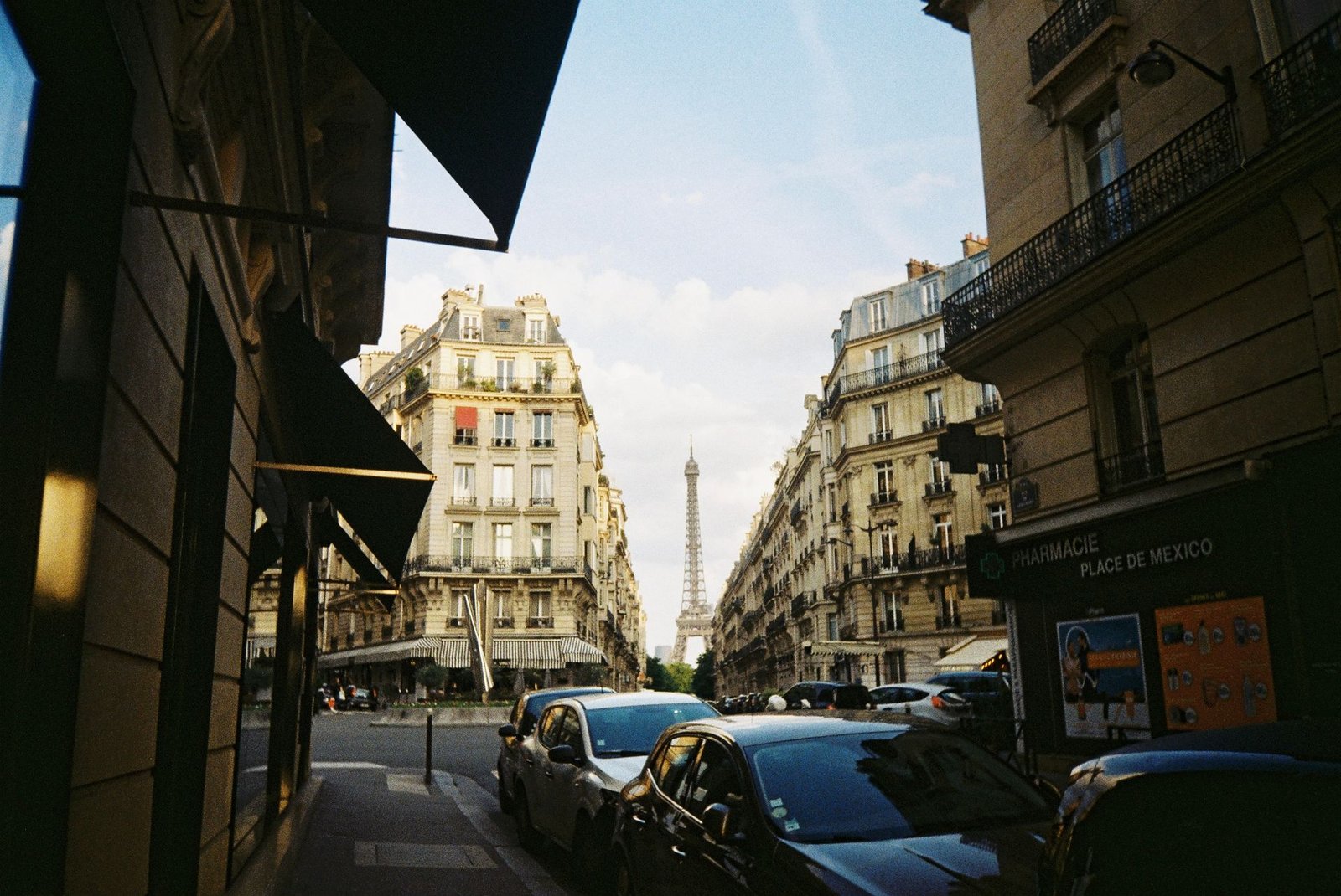 A Paris street lined with Haussmann buildings framing the Eiffel Tower