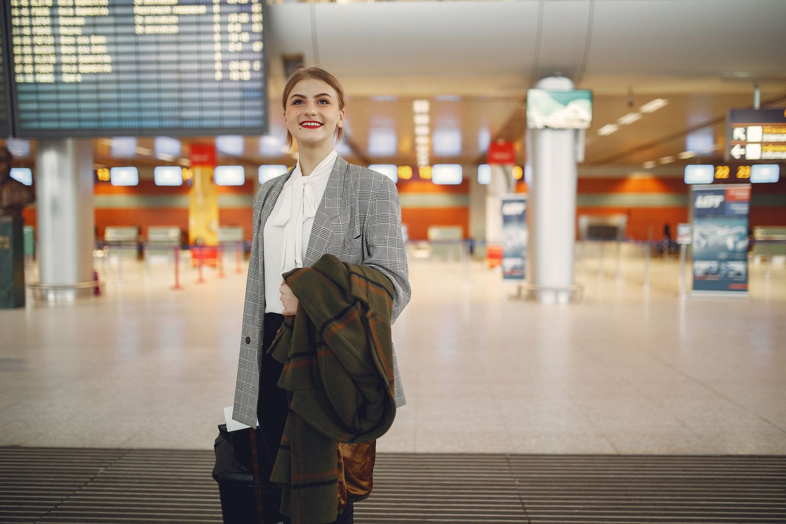 A traveler with a suitcase checking the departures board in an airport
