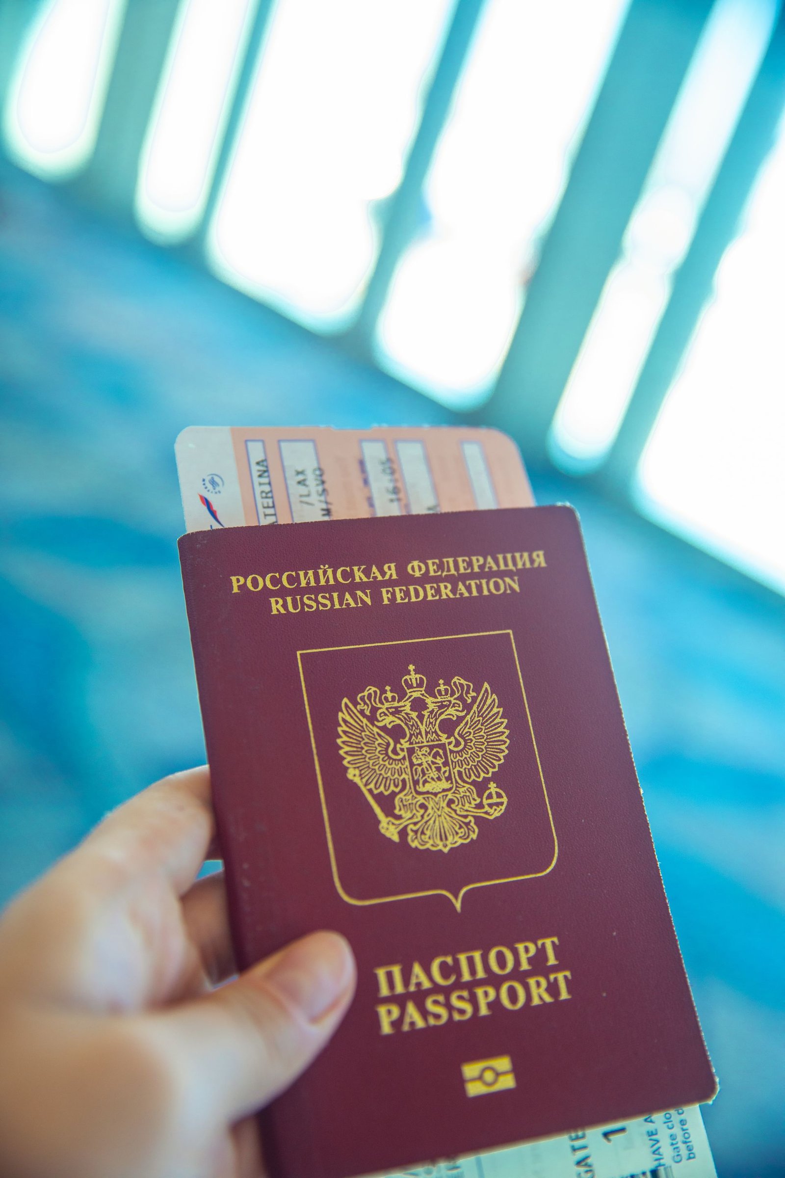 A hand holding a passport and boarding pass inside an airport terminal