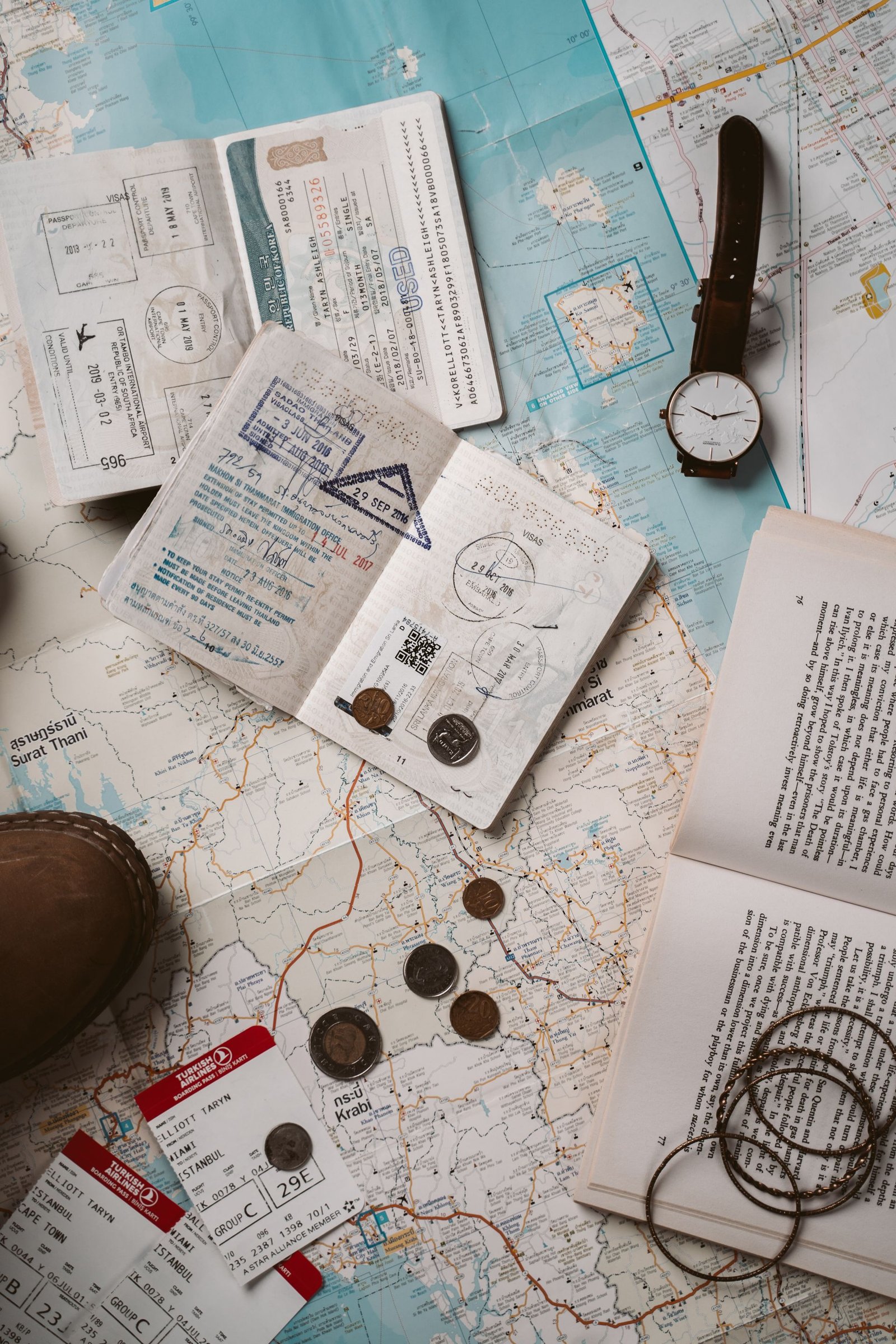 Passports, a paper map, a watch, and travel documents laid out on a table
