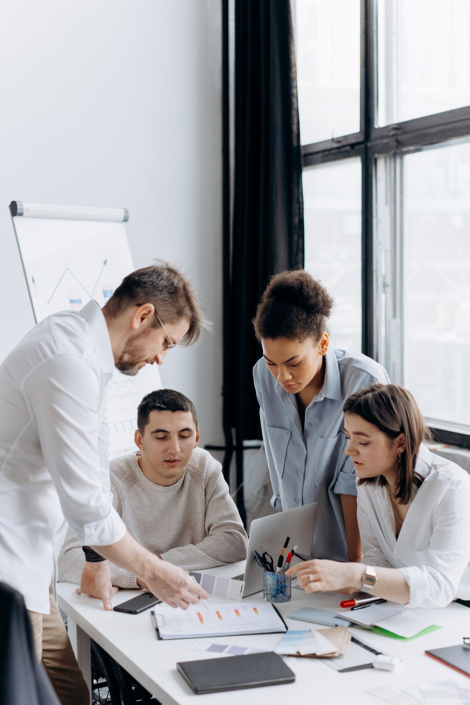 A team gathered around a white table, discussing notes and plans together