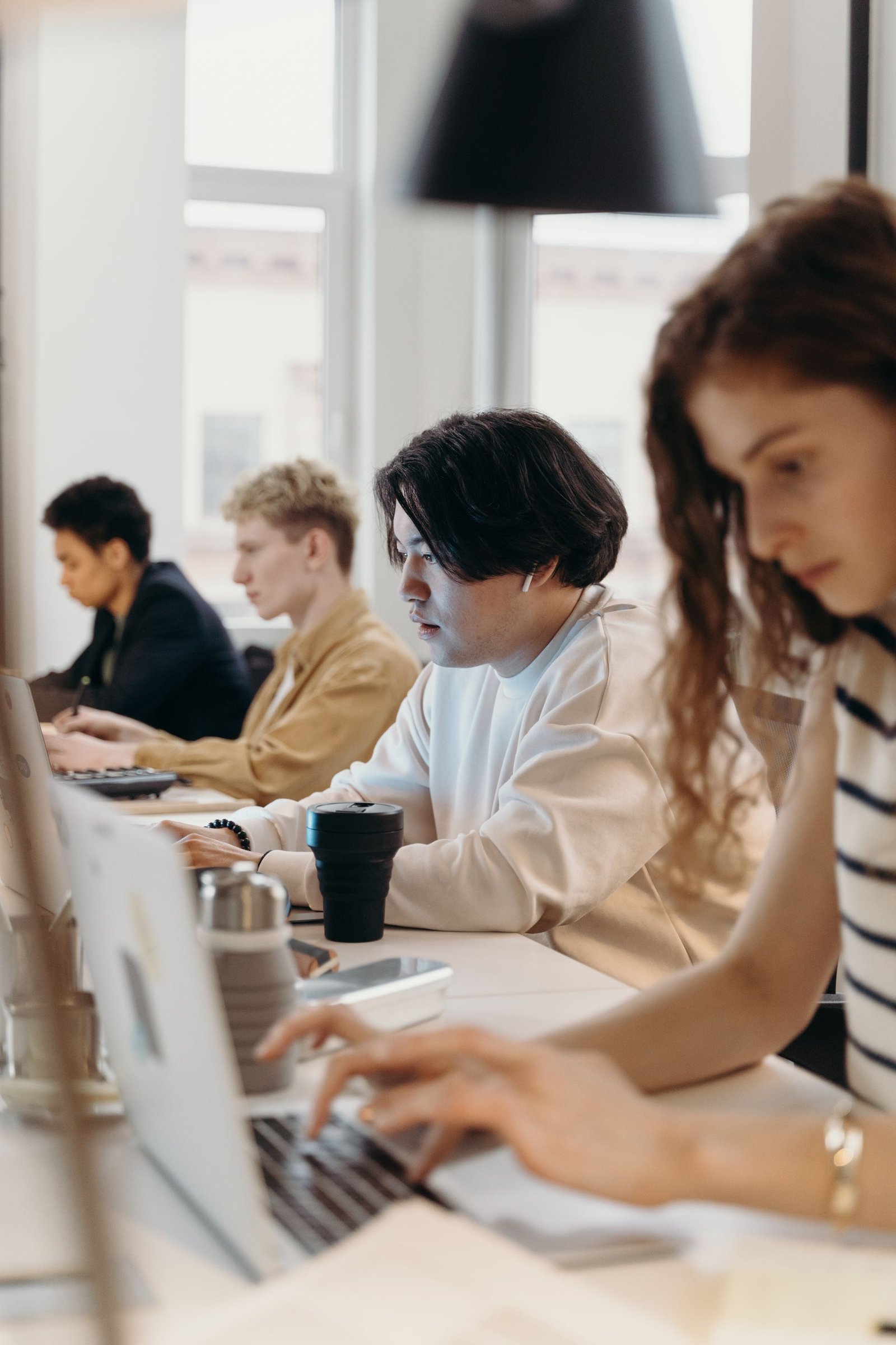 Colleagues working on laptops side by side at a long office desk