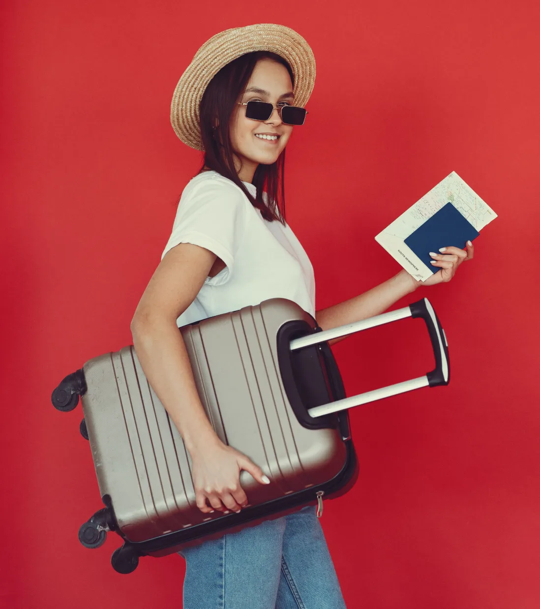 A smiling traveler in a sun hat carrying a suitcase and holding a passport and map